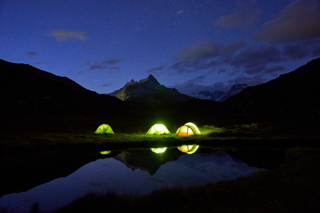 Tents glowing by a mountain lake at night, by Lukas Seitz via Pexels