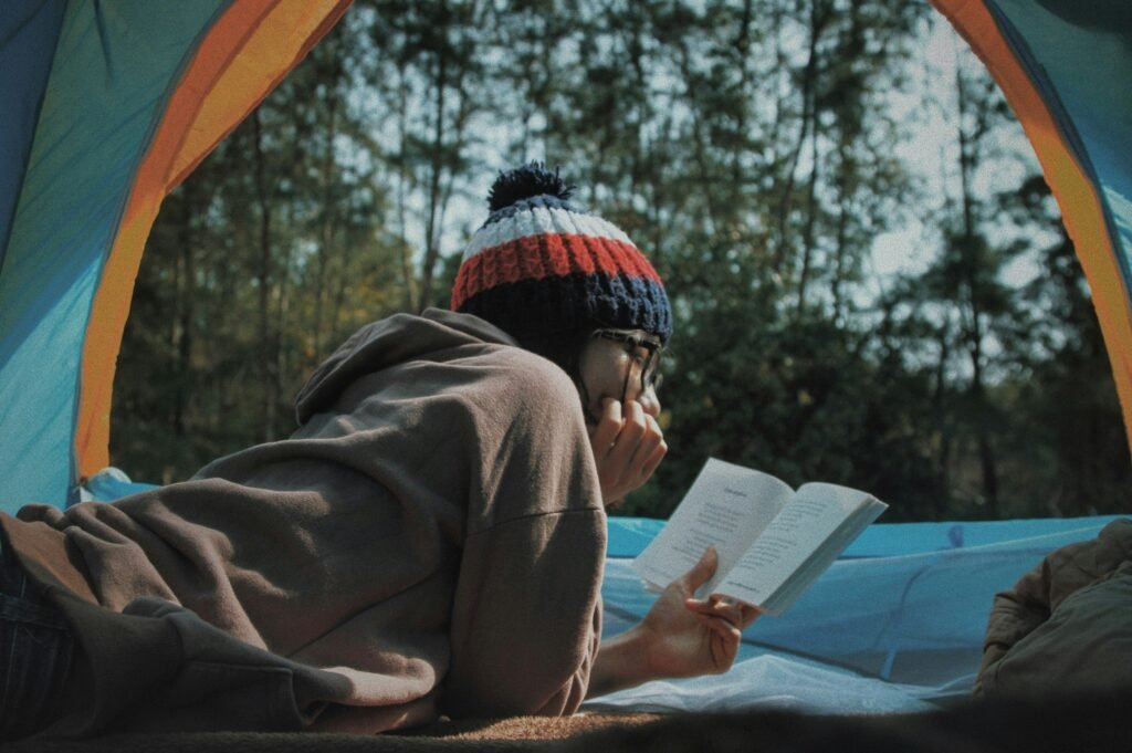 Woman relaxing and reading a book inside a cozy tent