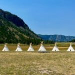 Group of teepees in a mountain field near Yellowstone National Park, representative of Yellowstone Tipis