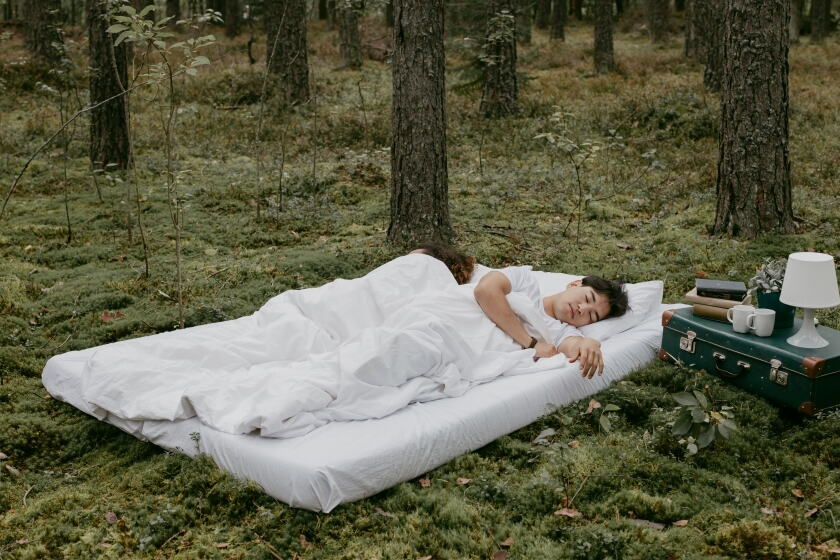Person resting on an air mattress outside at a campsite